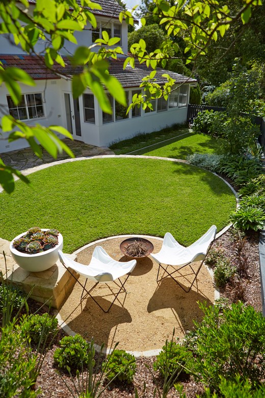 Landscape design with a circular lawn, sunken gravel fire pit area and layered garden planting.