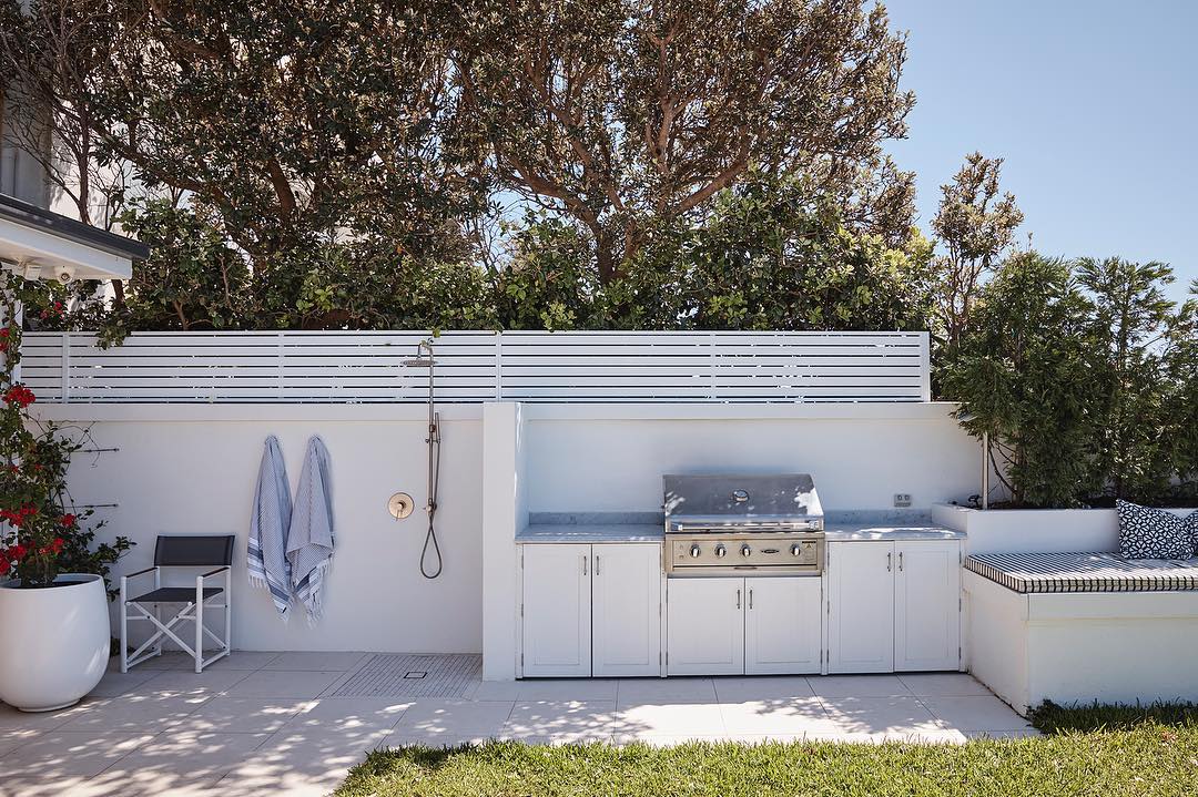 Backyard BBQ design featuring marble bench and shaker cabinets poolside