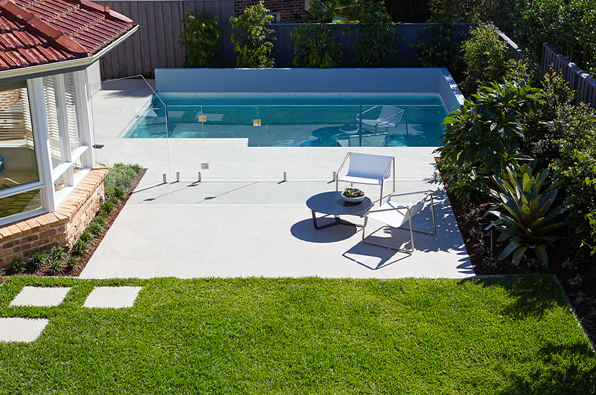Gallery Image Modern rectangular backyard pool with glass fencing, tiled patio and landscaped garden